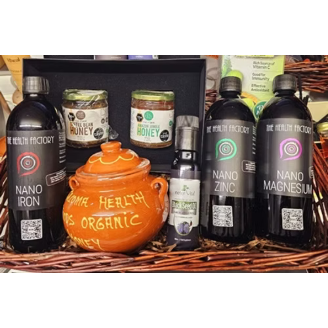 A gift hamper basket containing various health-related products including bottles labeled 'Nano Iron', 'Nano Zinc', and 'Nano Magnesium', jars of 'Manuka Honey' and 'Marmalade', and a small terracotta pot with the text 'Health is Organic'.