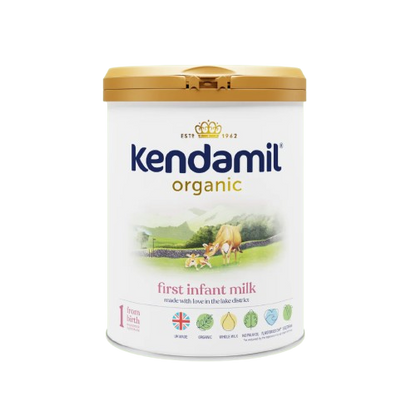 A canister of Kendamil Organic First Infant Milk, with a label showing a green field and cow , indicating it is organic.