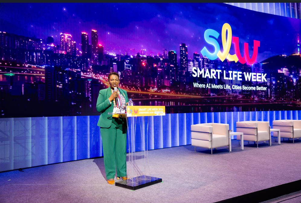 Perez Ochieng on stage in front of the Smart Life Week screen reading 'Where AI Meets Life, Cities Become Better'
